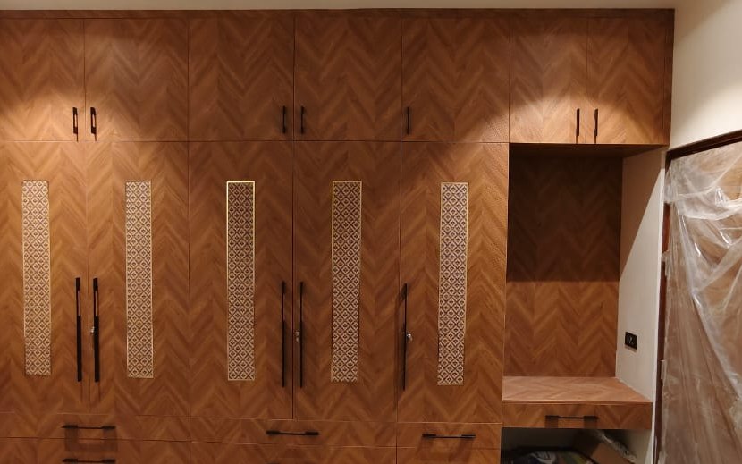 Wardrobe front in herringbone veneer with fluted inserts, by Padmodya Interiors